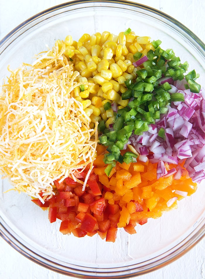 Ingredients for Frito Corn Salad in a glass bowl.