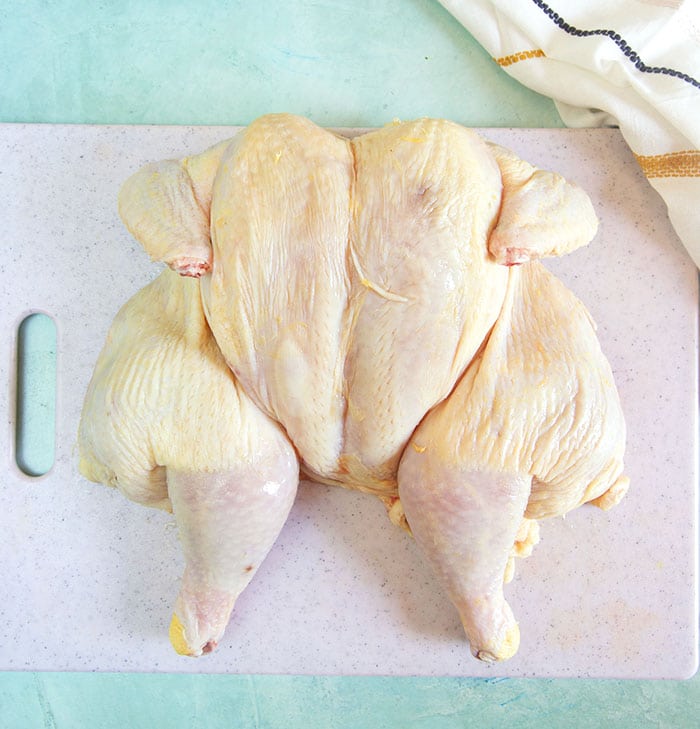 spatchcock chicken on a white cutting board.