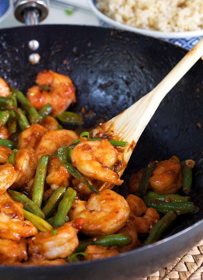 Hunan Shrimp in a stir fry pan with a wooden spoon.