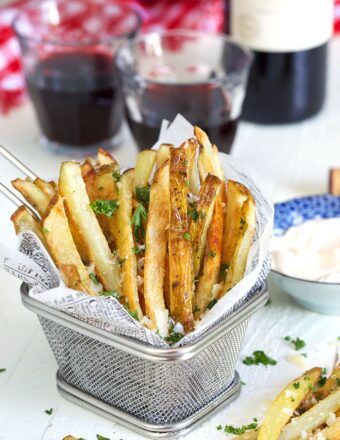 Parmesan Truffle Fries in a wire fry basket with parsley and a glass of wine.