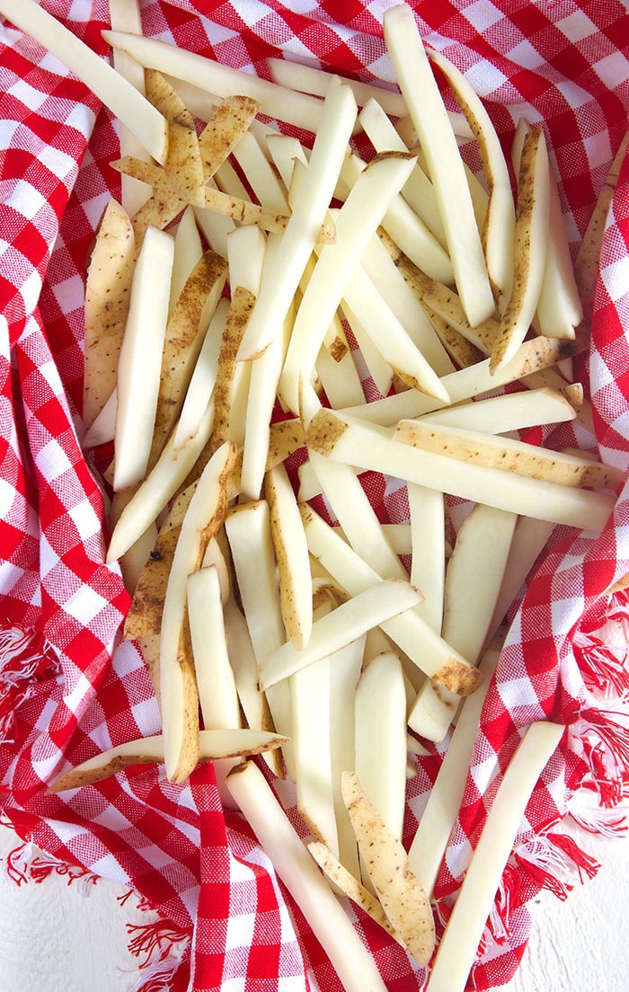 raw French fries on a red and white checkered towels.