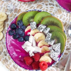 overhead shot of pitaya bowl smoothie bowl with blueberries, kiwi, coconut and raspberries.