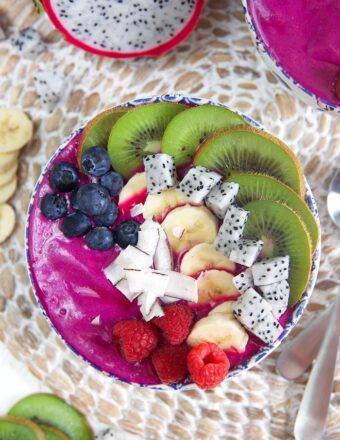 overhead shot of pitaya bowl smoothie bowl with blueberries, kiwi, coconut and raspberries.