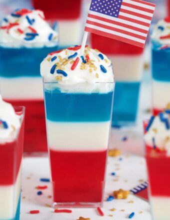 Red white and blue layered jello shots with an American flag on top.