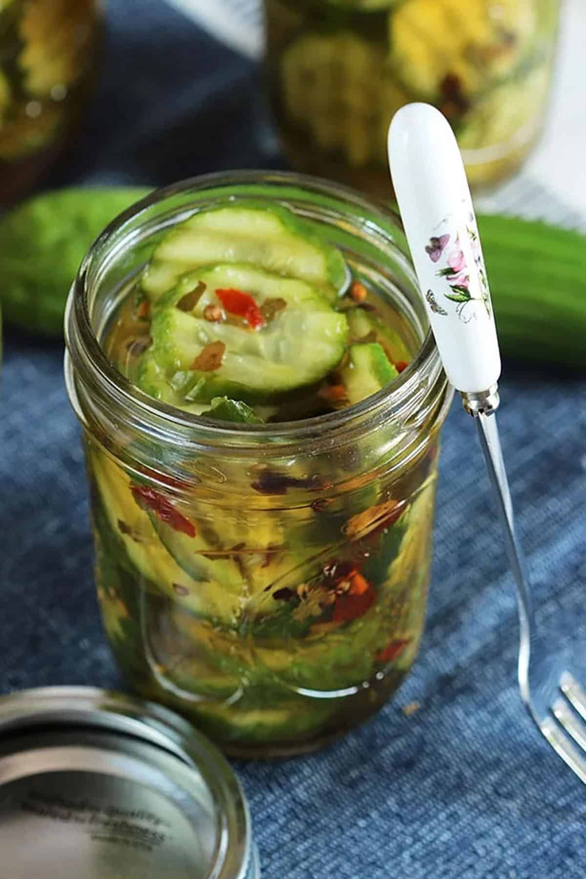 jar of pickles with a cute cocktail fork leading on the side.