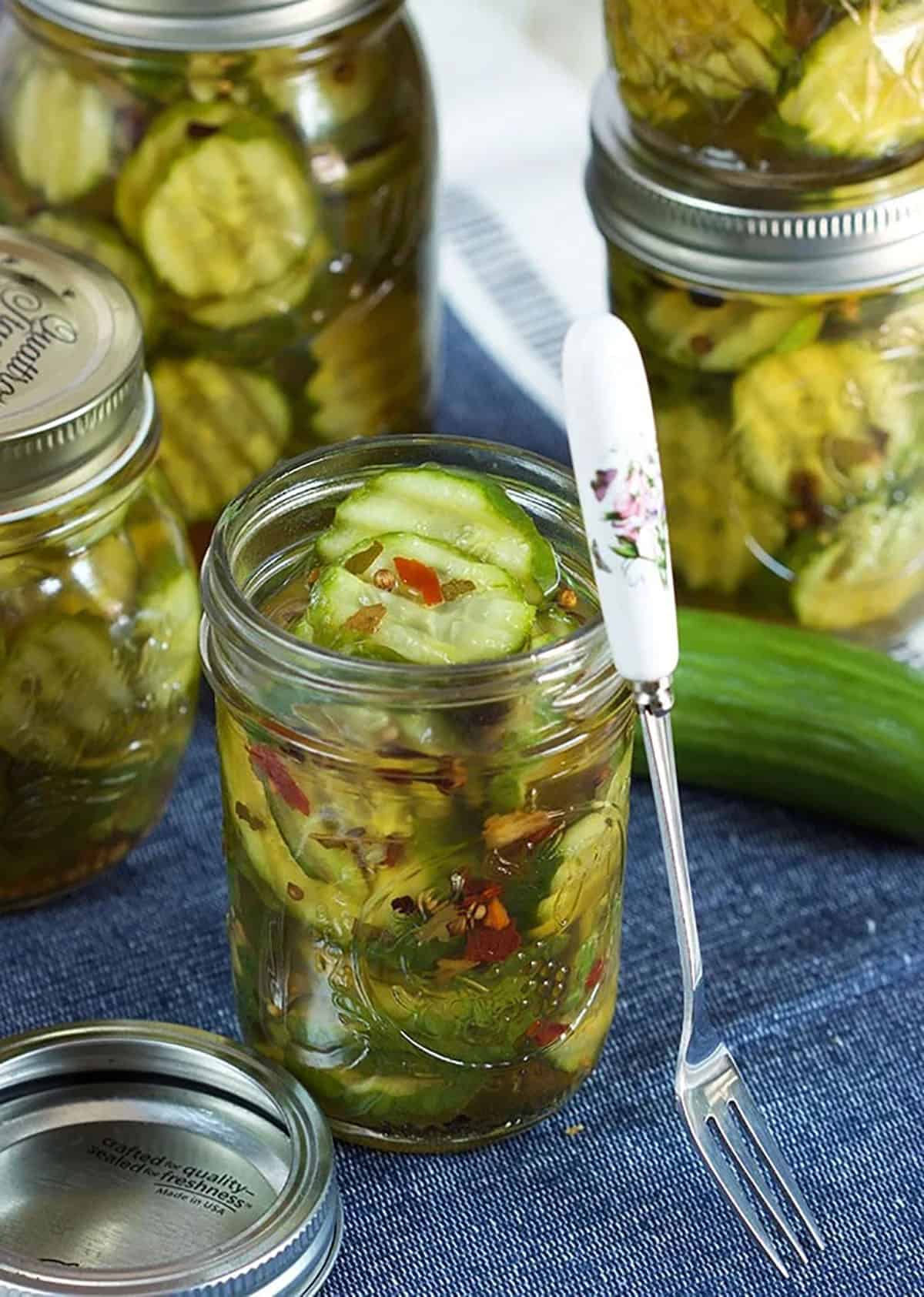 Bread and Butter Pickles in a jar with a cocktail fork leaning next to it.