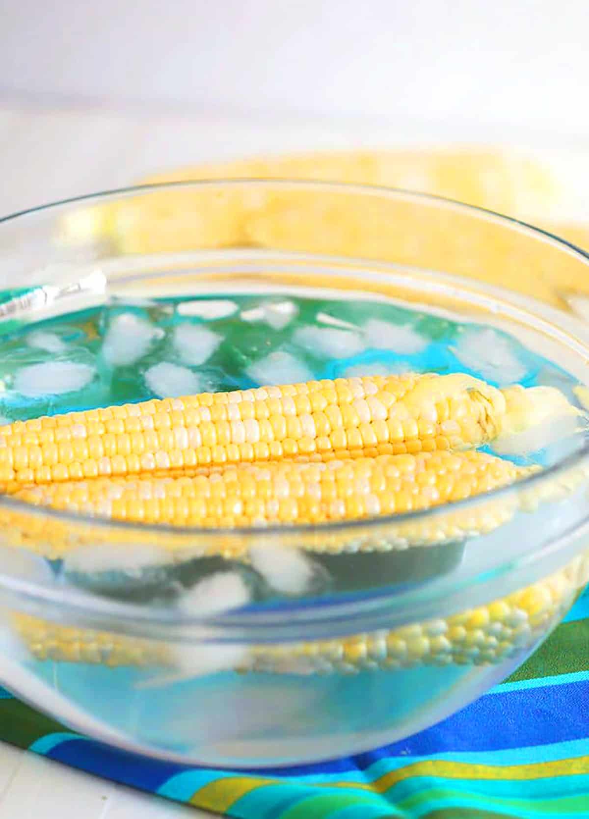 blanching corn on the cob in a glass bowl.