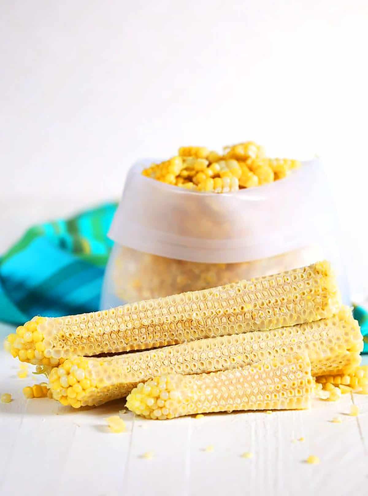 Corn off the cob in a freezer bag with cobs stacked in front.