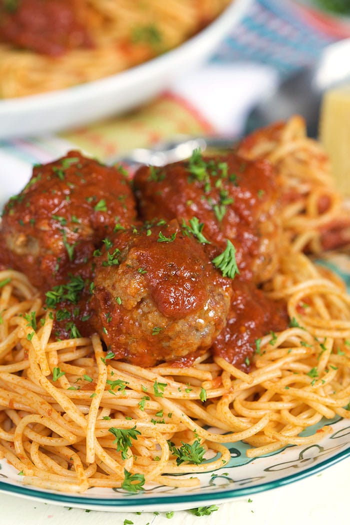 Fried meatballs on a pile of spaghetti on a white plate.