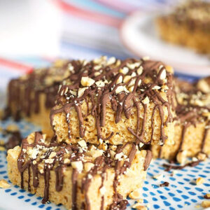 Peanut Butter Rice Krispie Treats stacked on a white plate with blue spots.