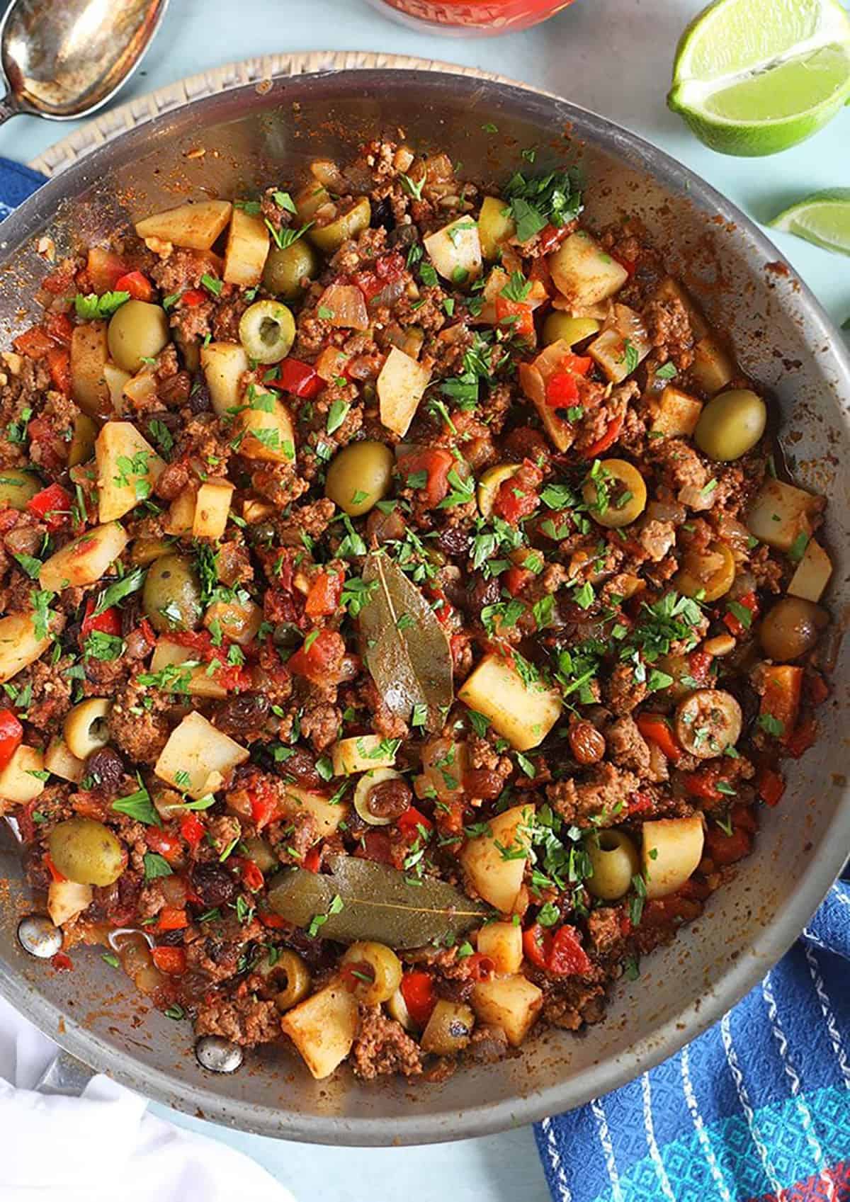 cuban Picadillo in a skillet with a lime.