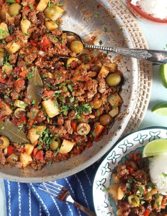 picadillo in a skillet with a silver spoon.