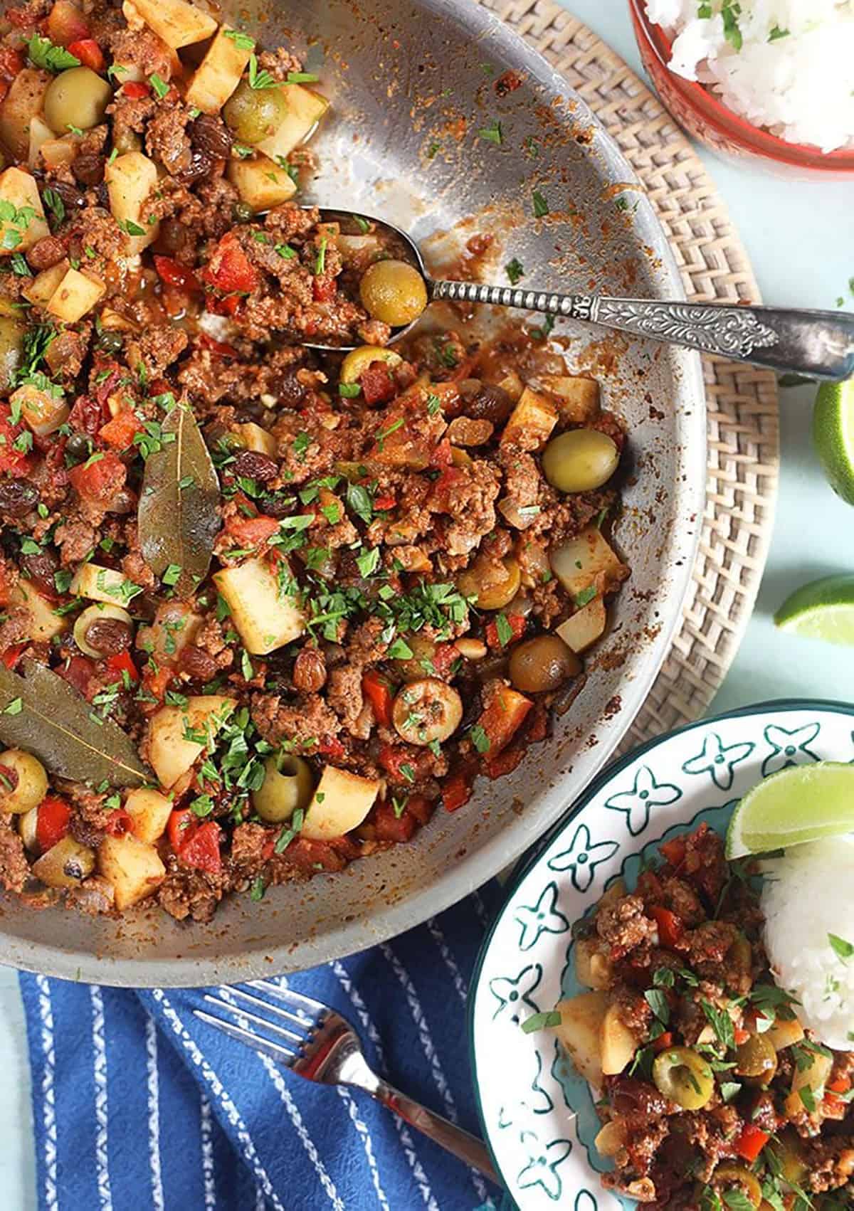 picadillo in a skillet with a silver spoon.