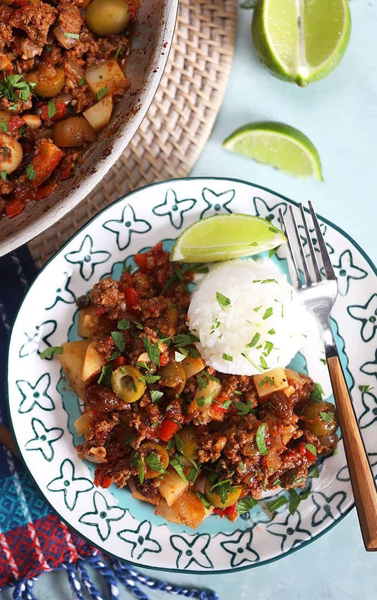 picadillo on a plate with rice and a wooden spoon.