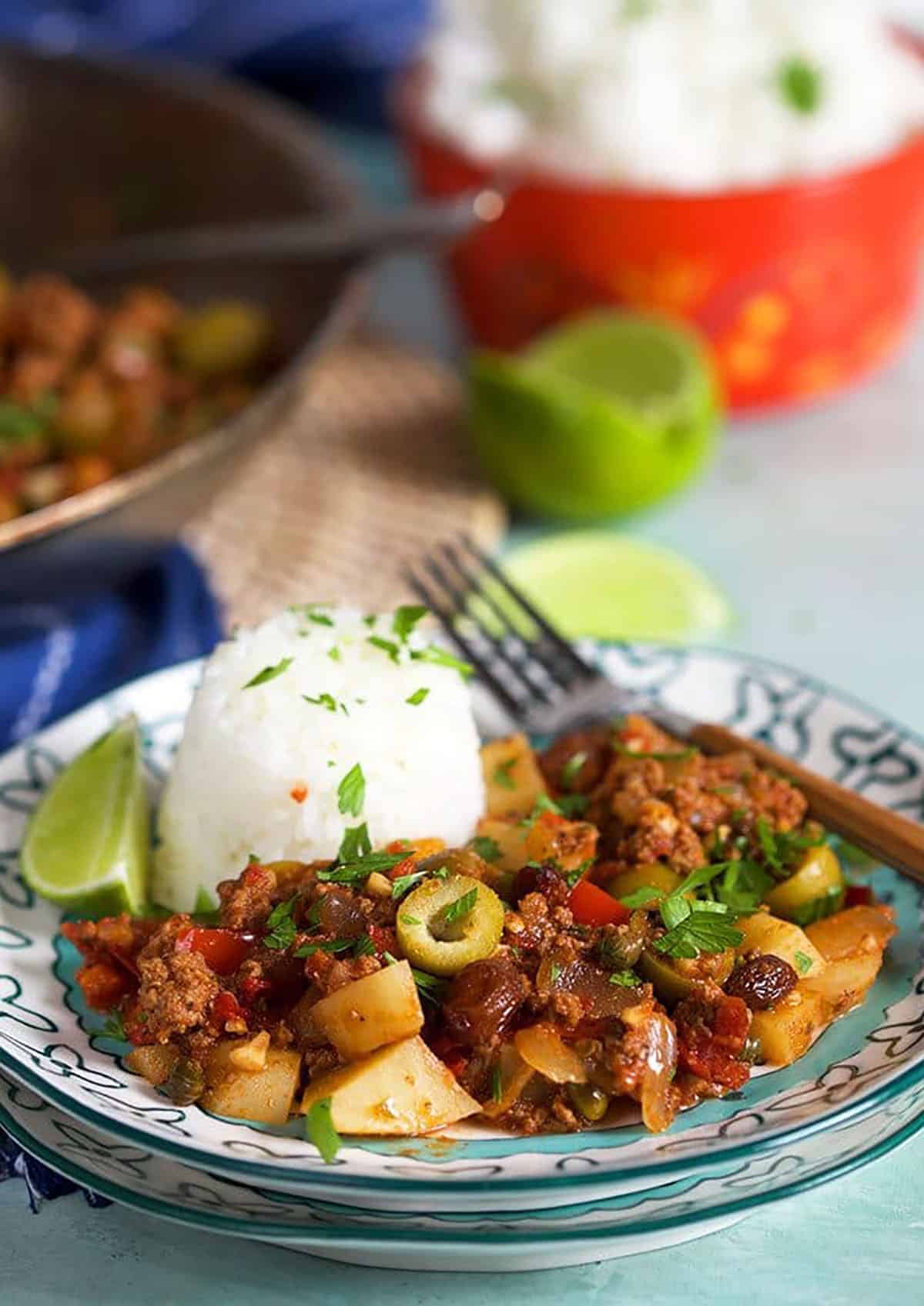Cuban Picadillo on a plate with a fork and rice.
