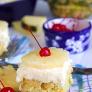 Pineapple Sunshine Cake on a plaid plate with pineapple and a cherry on top.