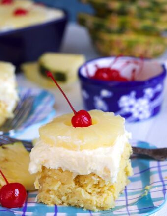 Pineapple Sunshine Cake on a plaid plate with pineapple and a cherry on top.