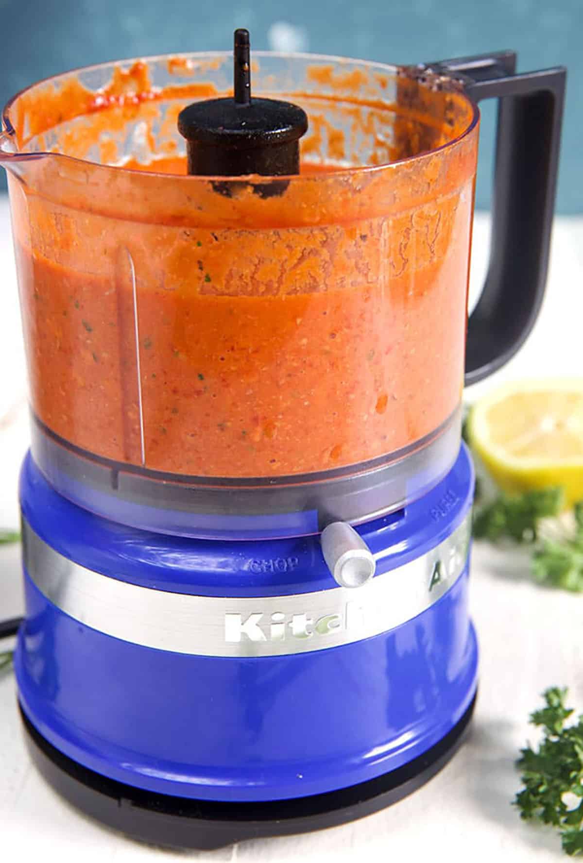 Romesco Sauce in a food processor with a blue background.