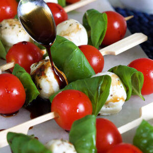 Caprese Salad Skewers with balsamic glaze being drizzled over it.