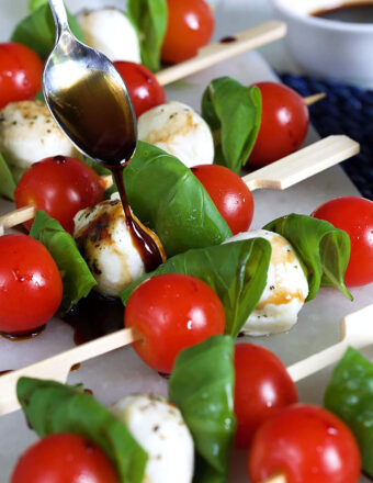 Caprese Salad Skewers with balsamic glaze being drizzled over it.