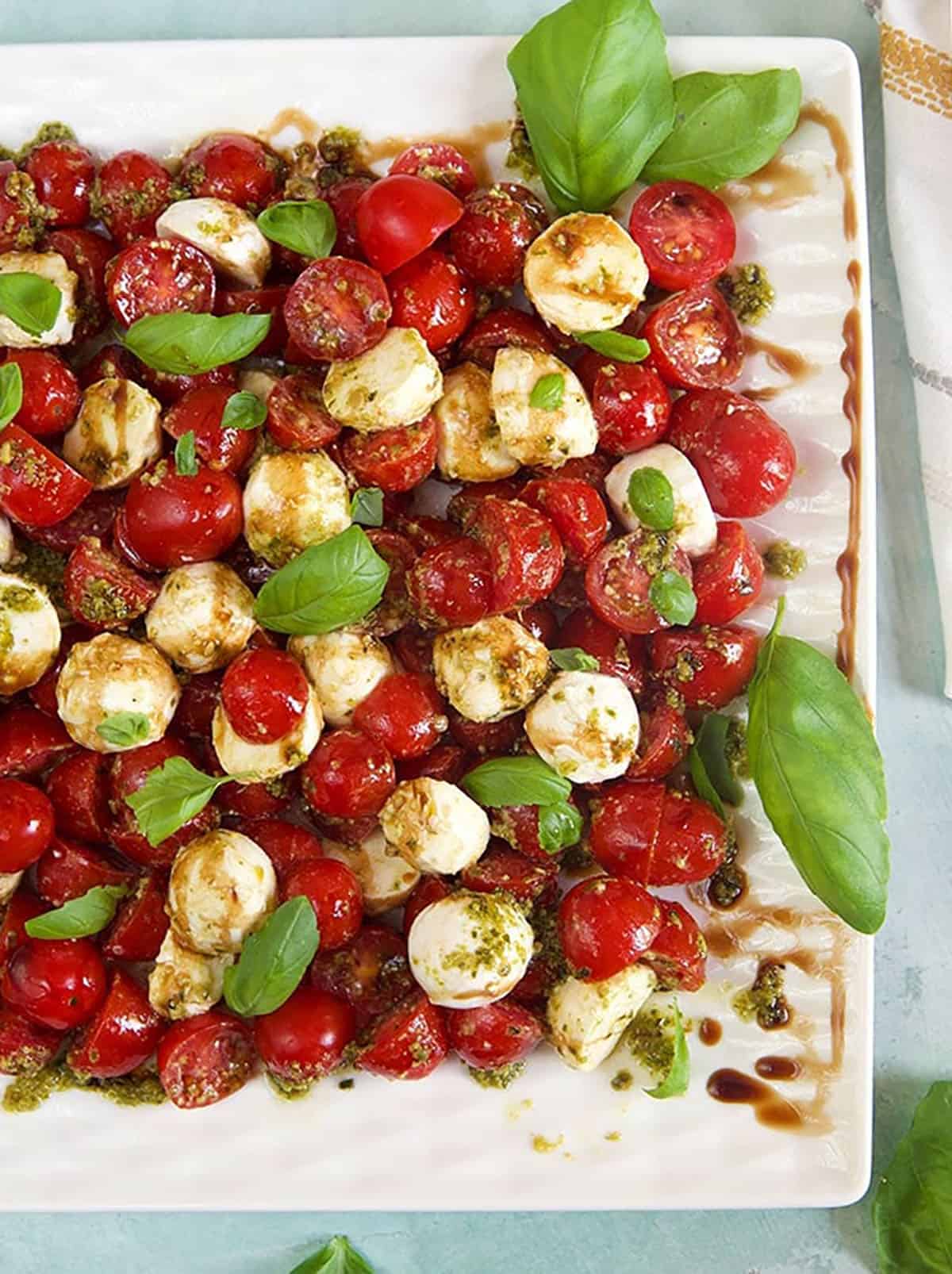 Caprese Salad on a square platter with basil.