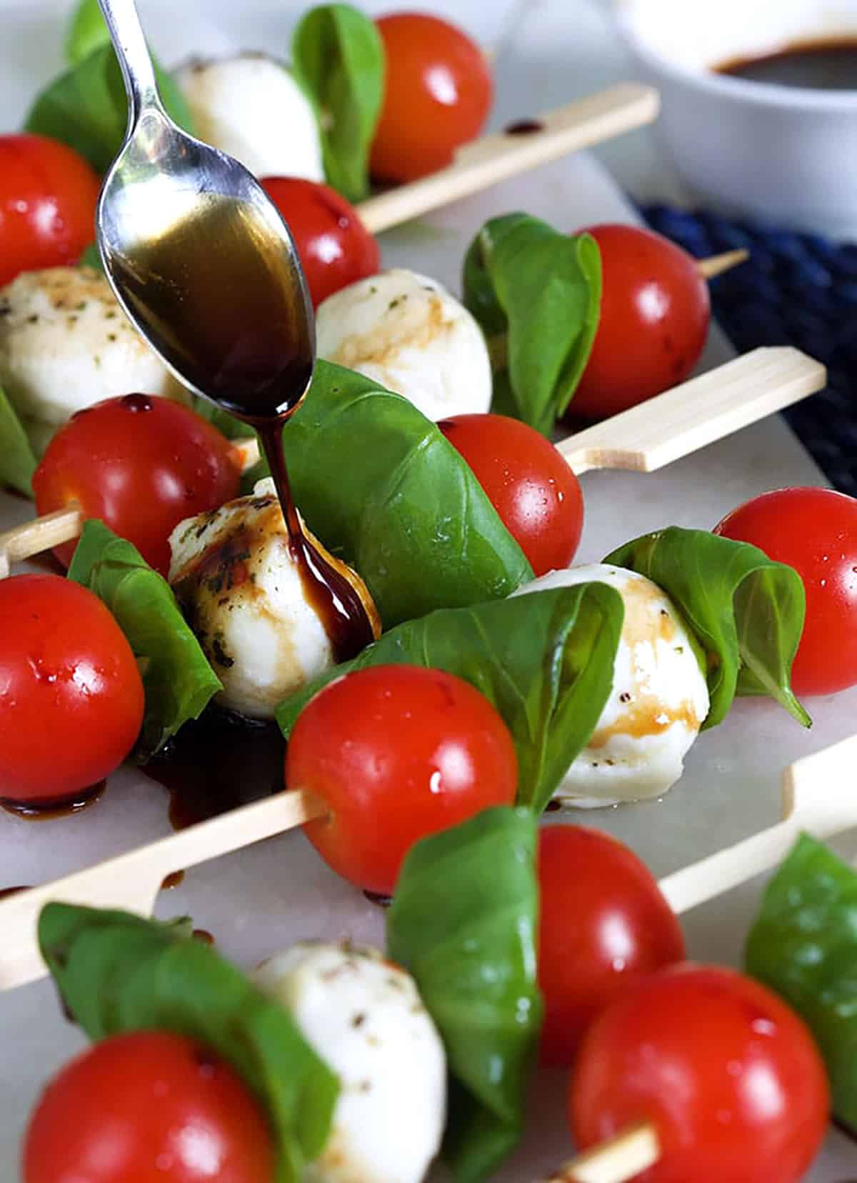 Caprese Salad Skewers with balsamic glaze being drizzled over it.