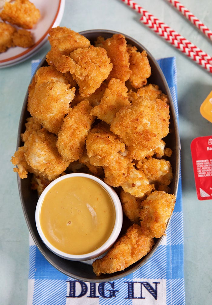 Chick-Fil-A Nuggets in a metal serving pan with sauce on a blue and white checked napkin.
