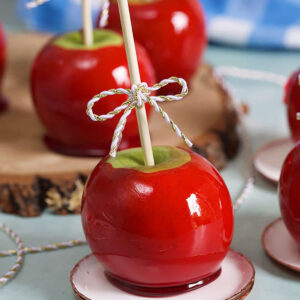 Candy apples on a wood slice on a blue background.