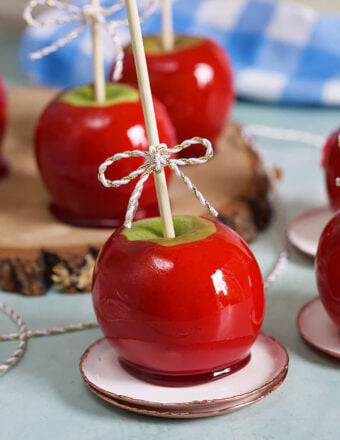 Candy apples on a wood slice on a blue background.