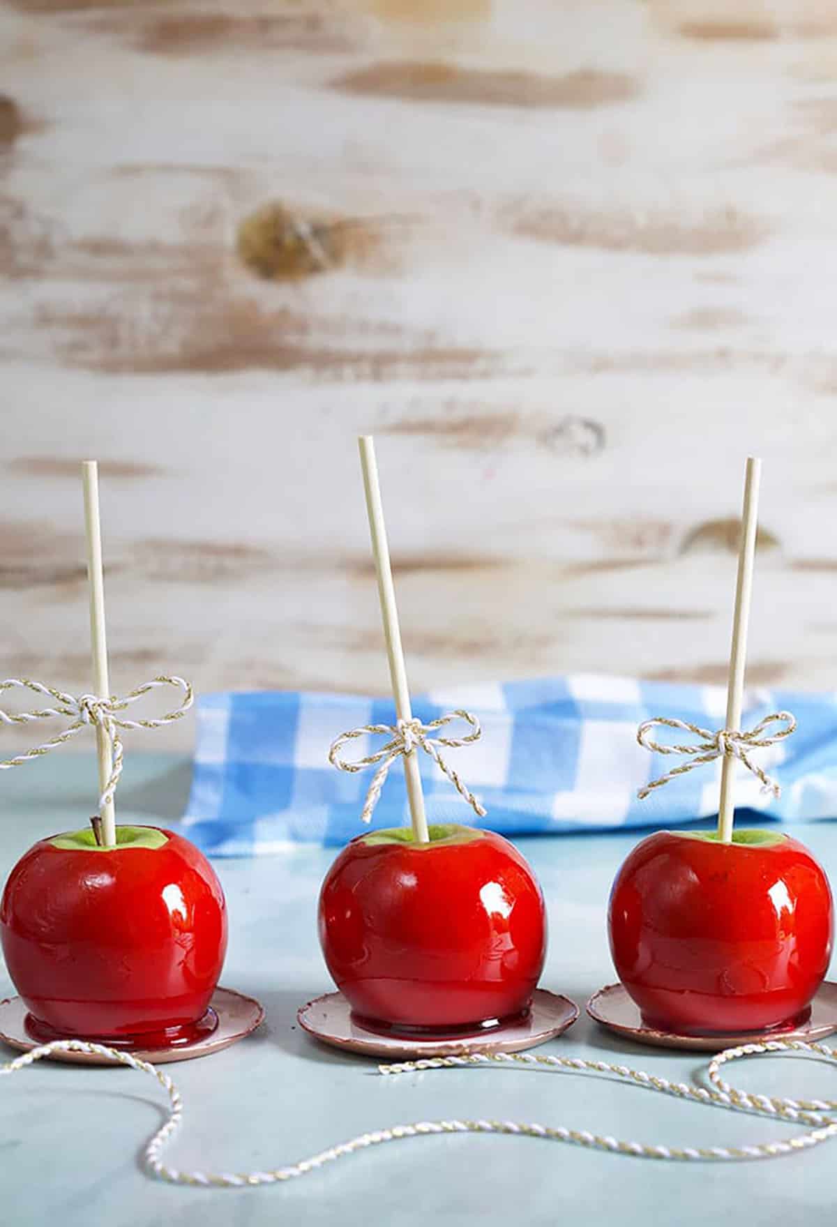 Three candy apples in a row on a blue background.