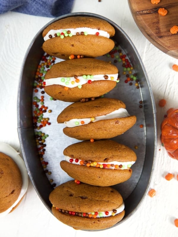 Overhead shot of pumpkin whoopie pies in an oval steel tray.