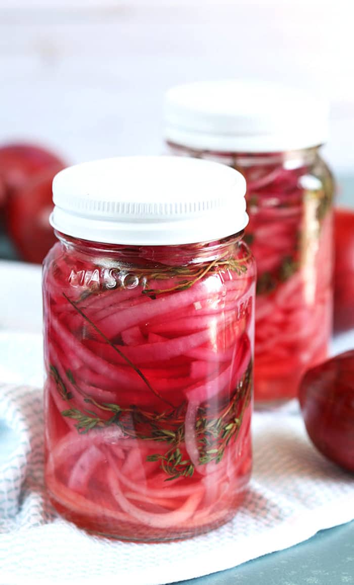 pickled red onions in a jar with a white lid.