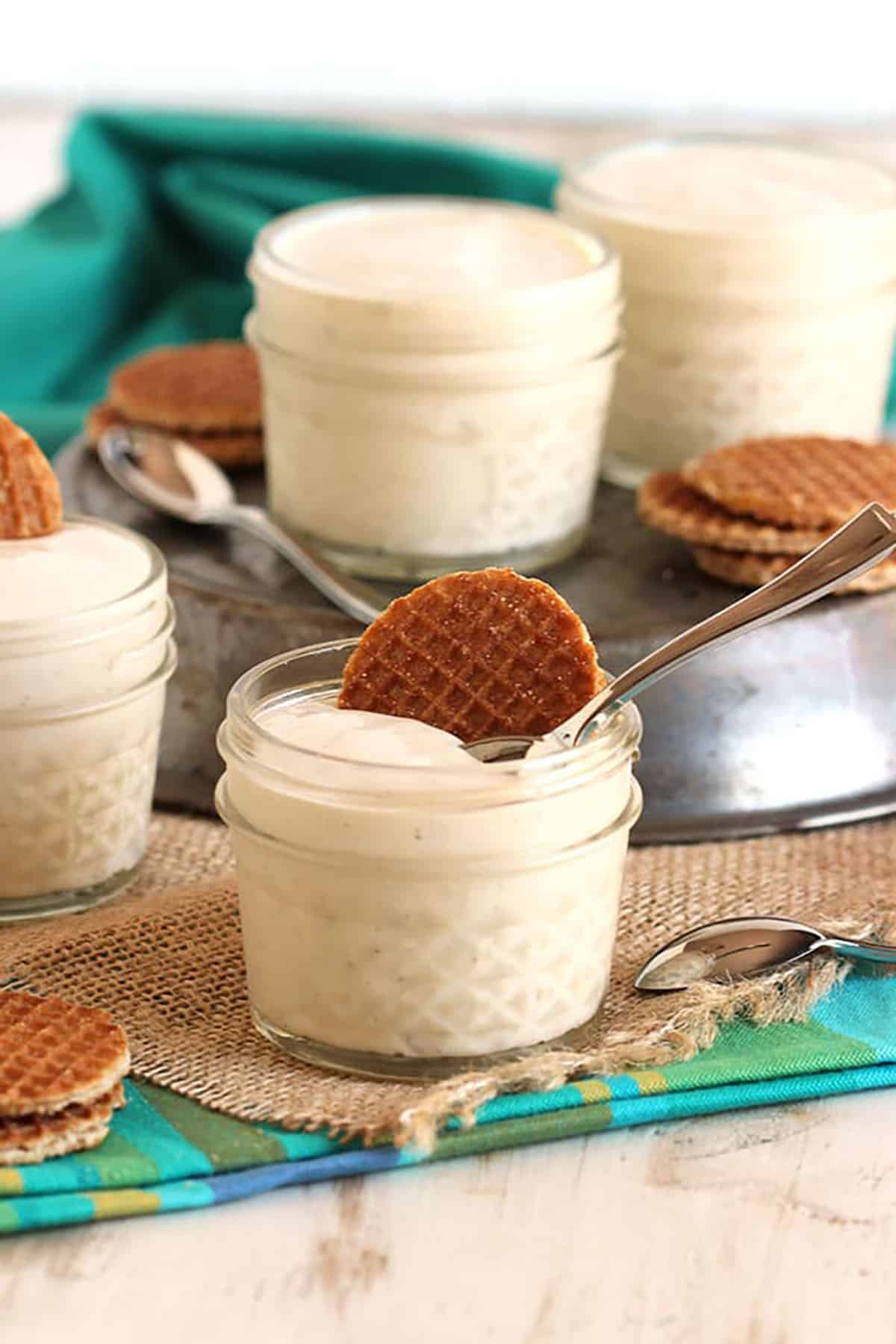 Vanilla PUdding in a small glass jar with a mini stroopwafel on top. Jar is placed on a small piece of burlap.
