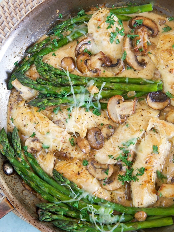 Cheesecake Factory Chicken Madeira in a skillet with asparagus.