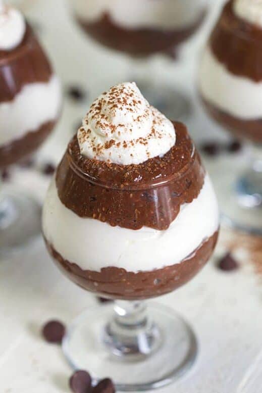 Chocolate Chia Pudding parfaits in mini wine glassed on a white background.