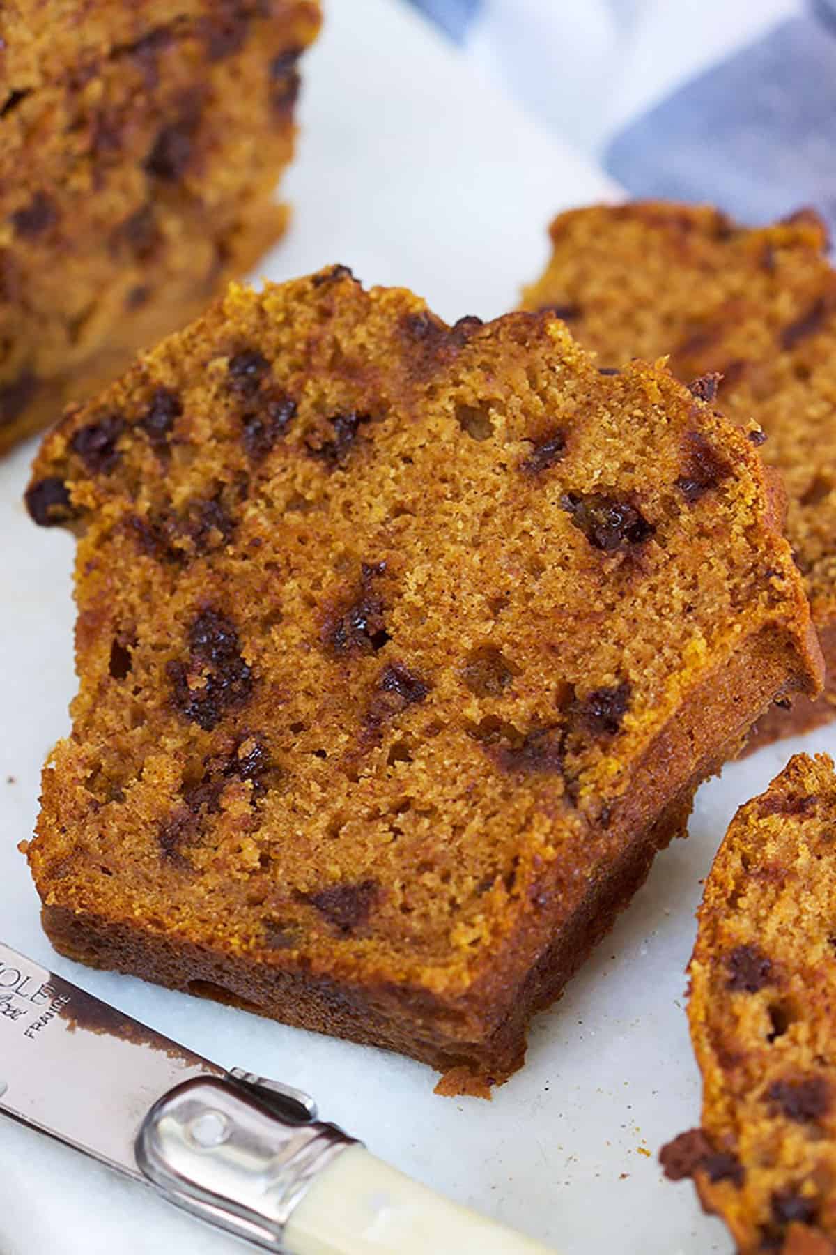 Slice of Chocolate Chip Pumpkin Bread on a white board.