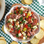 Hoagie dip in a white bowl with crostini around it.
