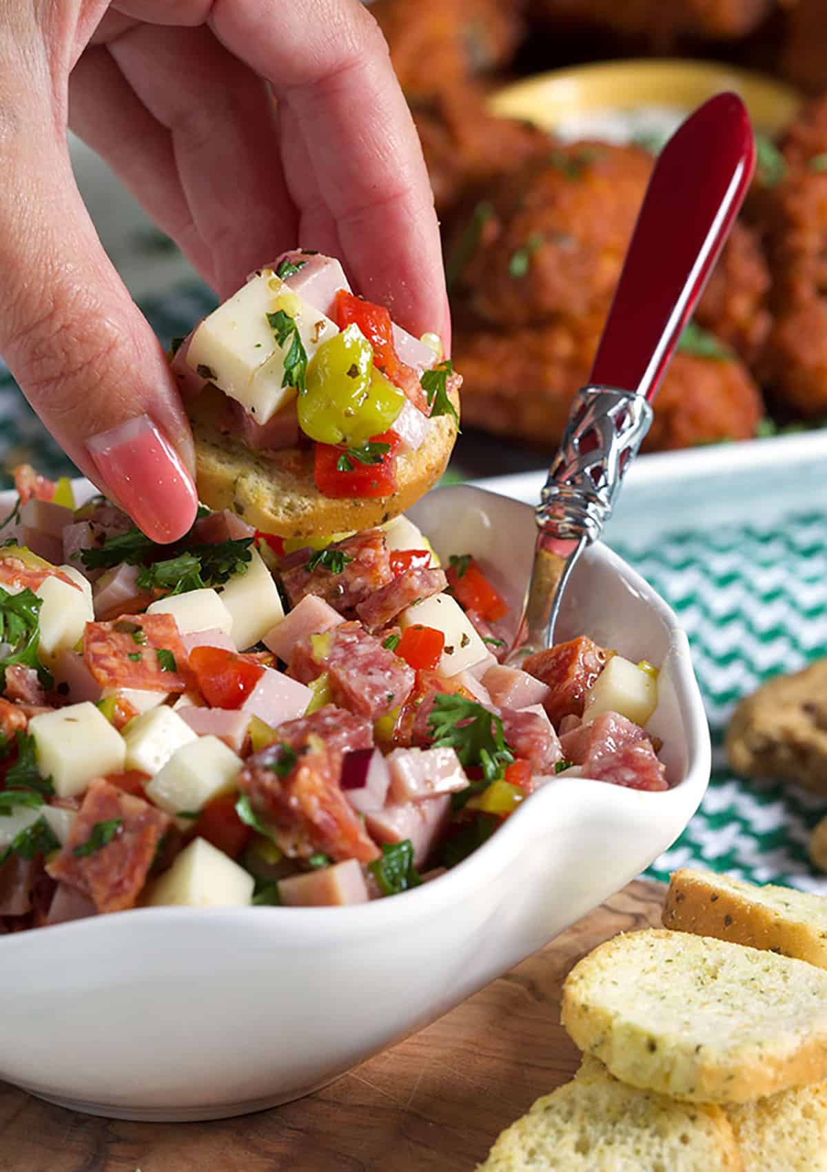 Hoagie dip on a crostini with a hand holding it.