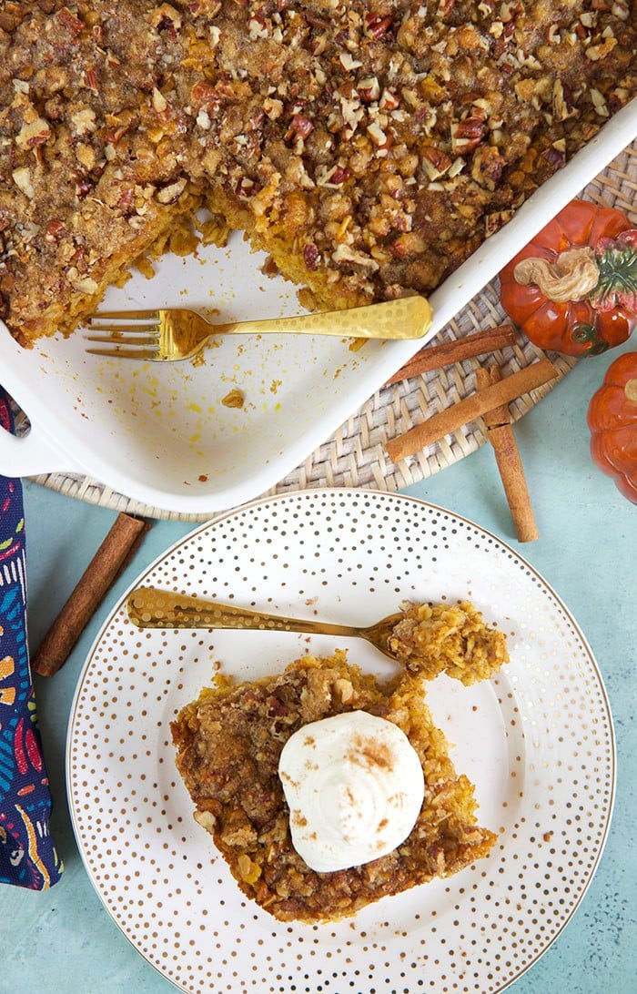 Overhead shot of pumpkin baked oatmeal in a baking dish with a slice on a white plate.