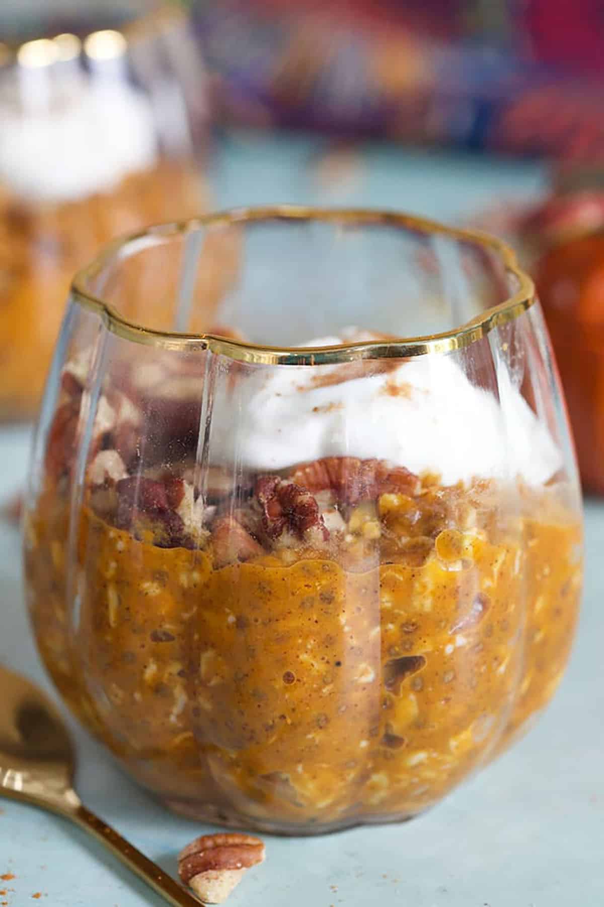 close up of pumpkin oats in a glass with a gold spoon.