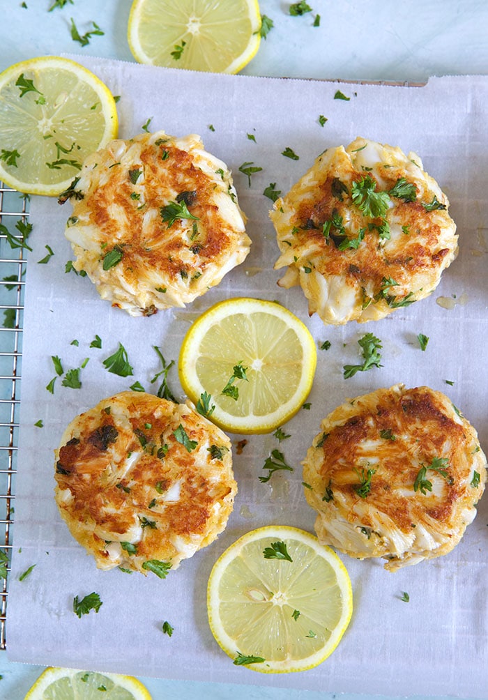 crab cakes on parchment on a cooling rack with lemon.