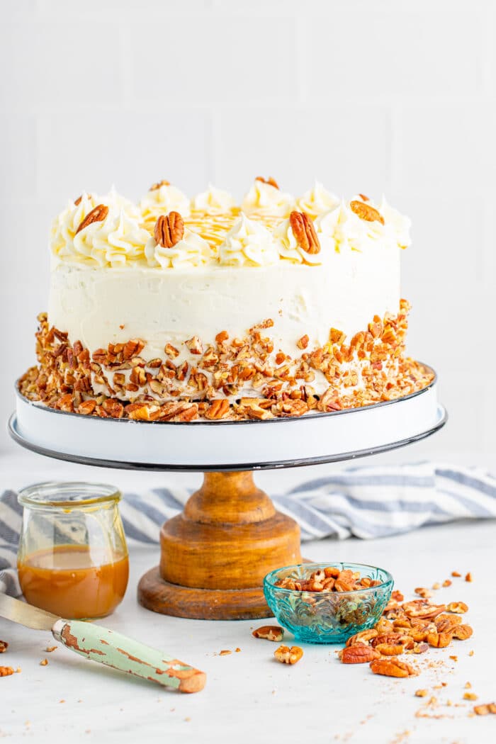 Bourbon Butter Layer Cake on a cake stand with caramel sauce in a jar.