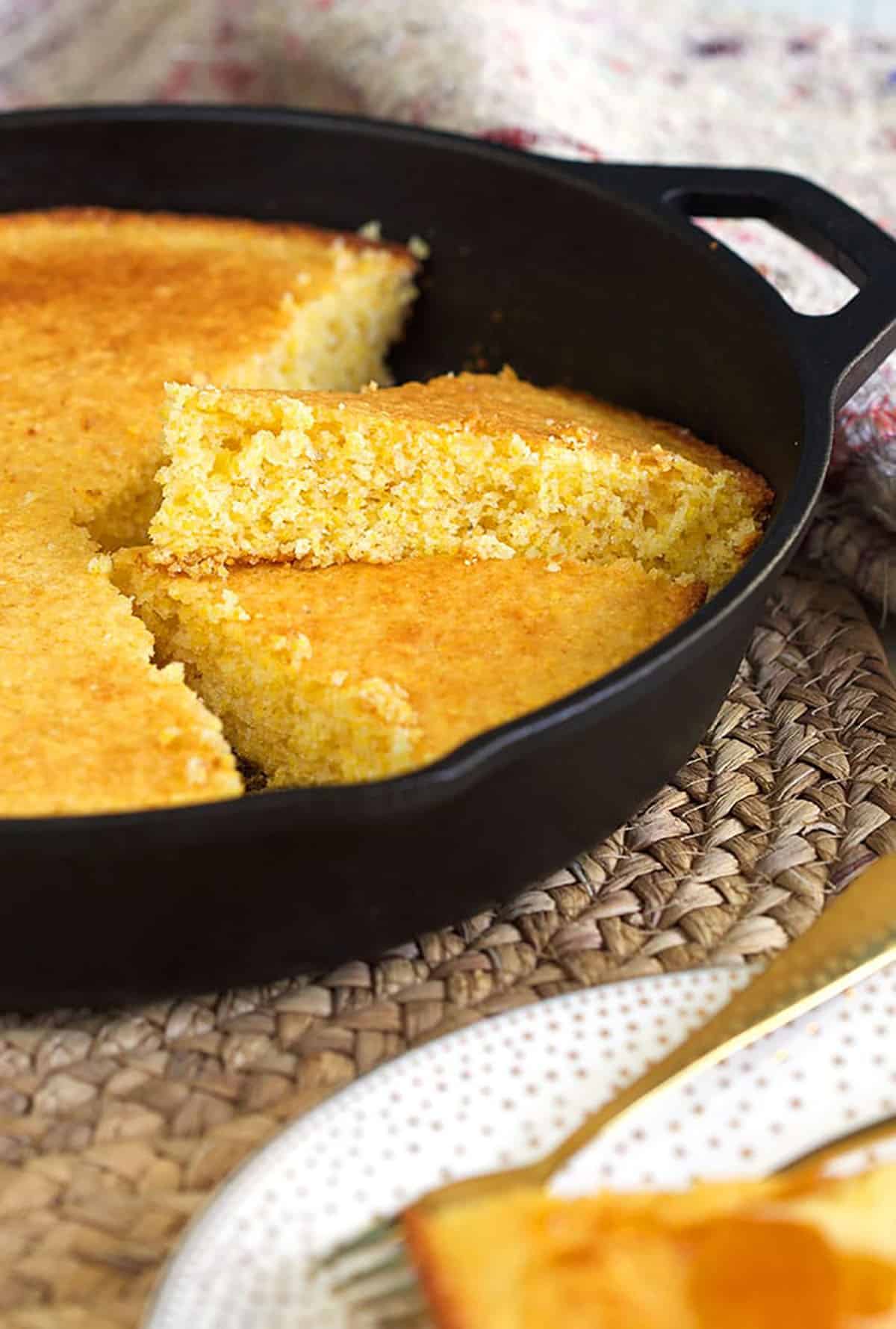 Cornbread is sliced in pieces in a black skillet.