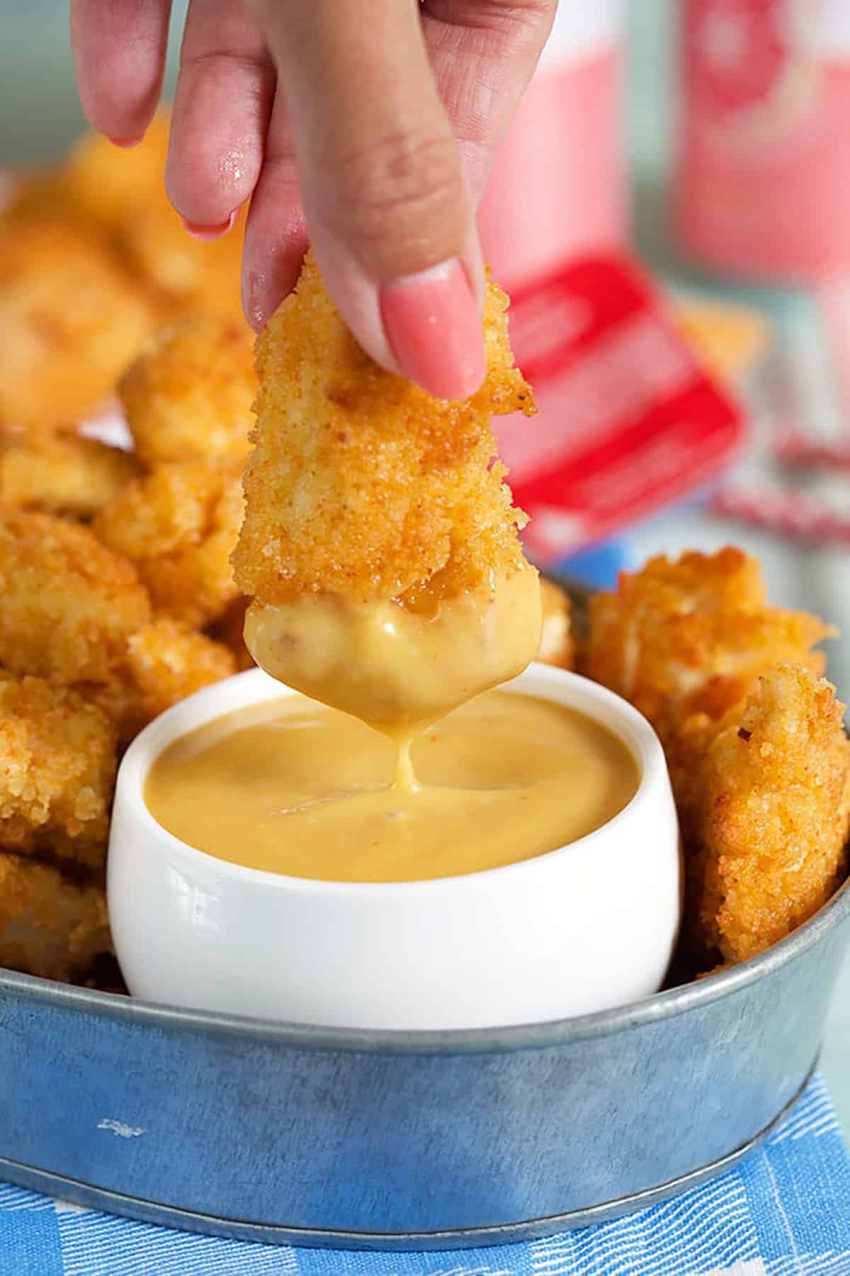 chicken nugget being dipped in sauce.