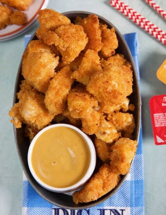 Chick-Fil-A Nuggets in a metal serving pan with sauce on a blue and white checked napkin.