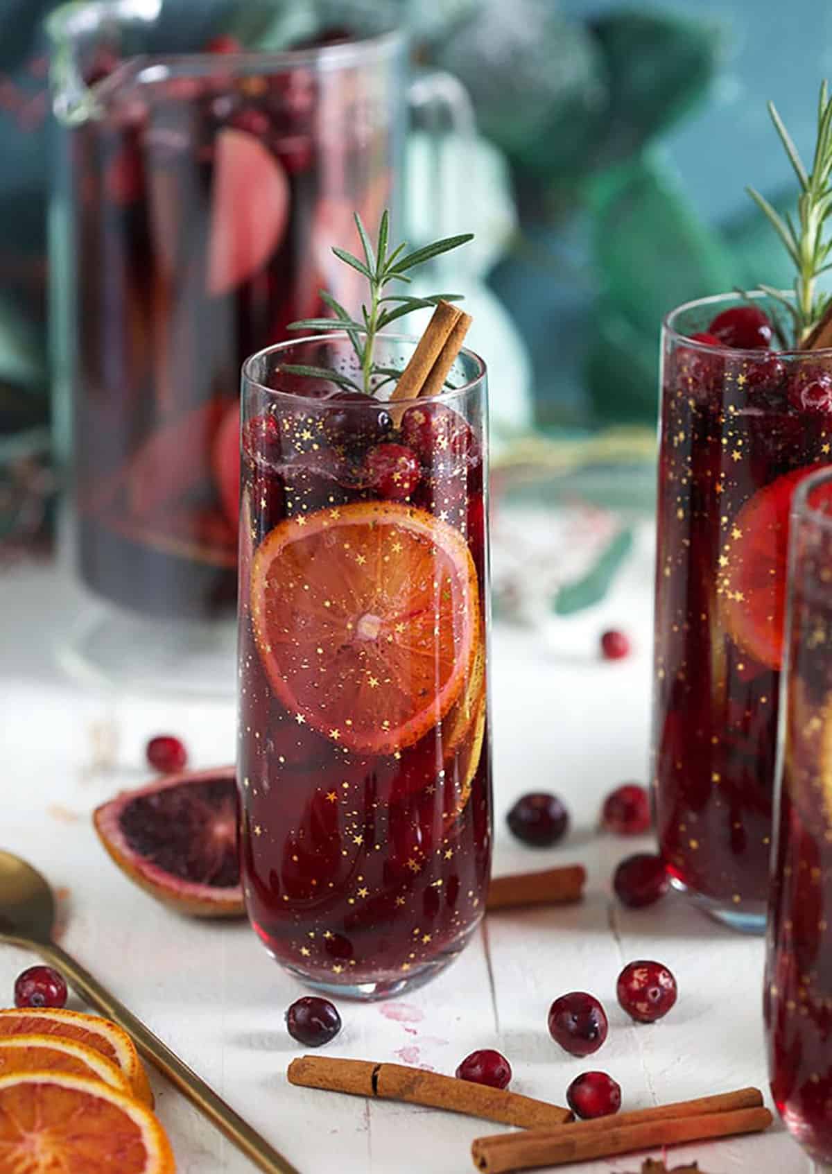 three glasses filled with Christmas sangria on a white background.
