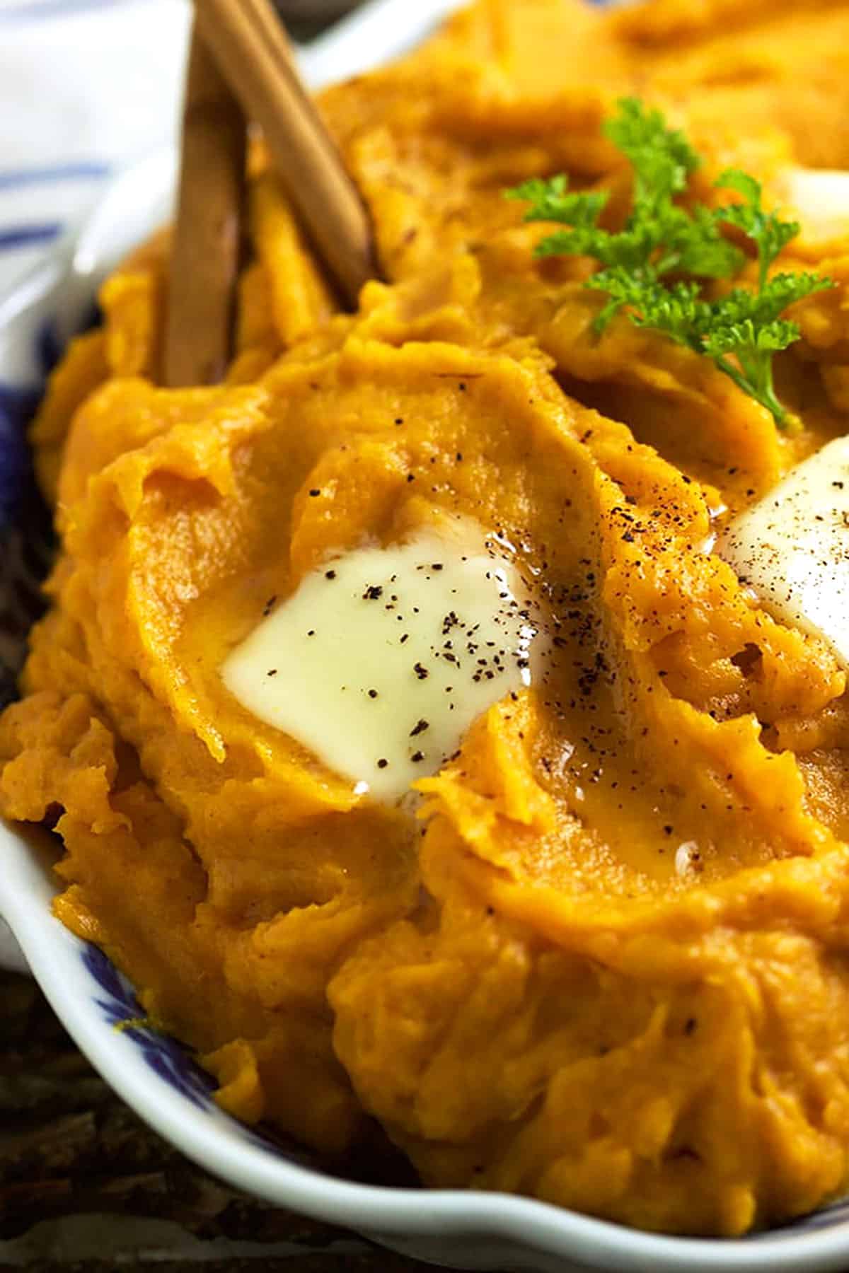 mashed sweet potatoes in a blue and white bowl with two cinnamon sticks on top.