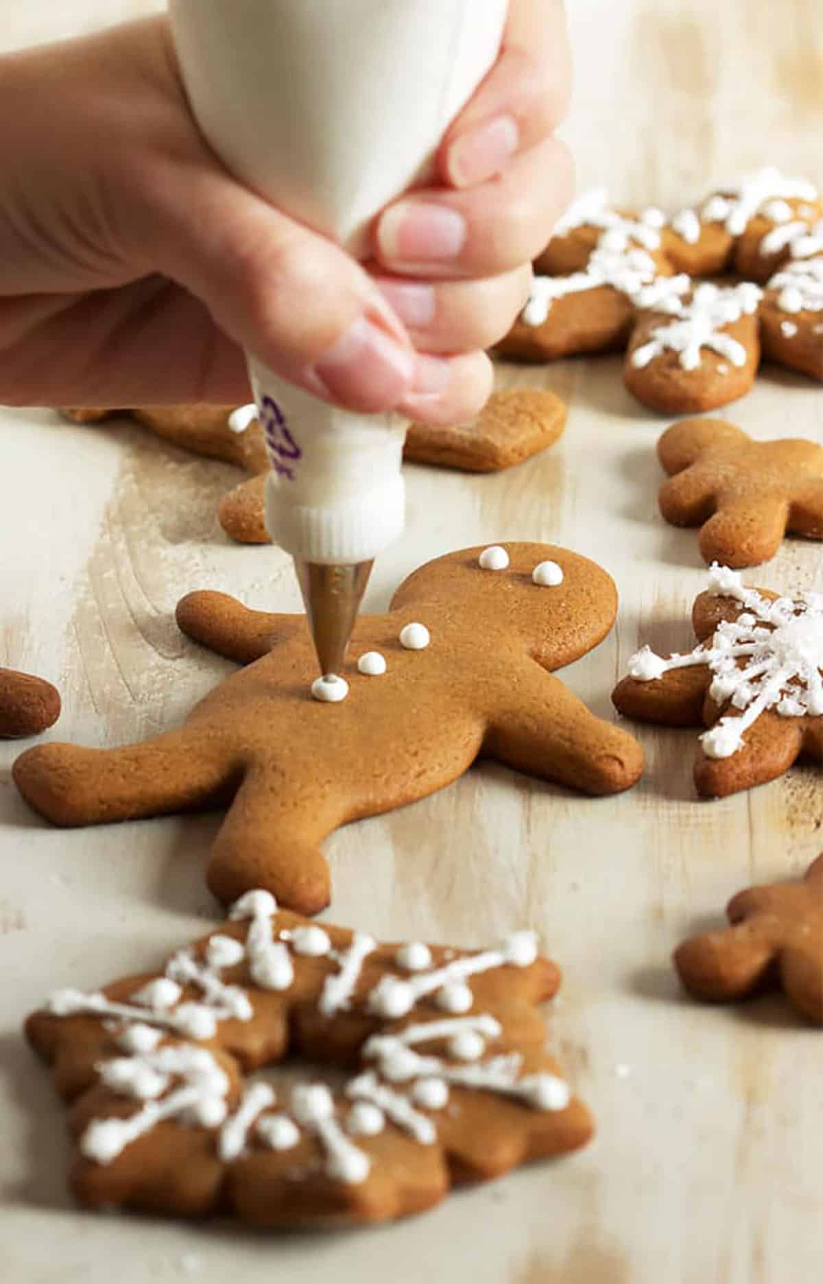 Royal Icing being piped onto a gingerbread man cookie