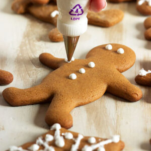 gingerbread man cookie being decorated with a piping bag