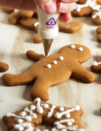 gingerbread man cookie being decorated with a piping bag
